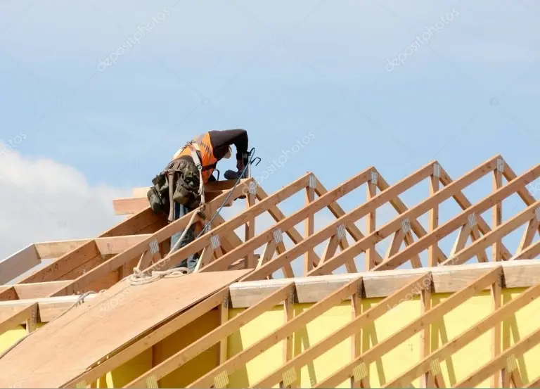 osoba pracująca na drewnianej więźbie dachowej